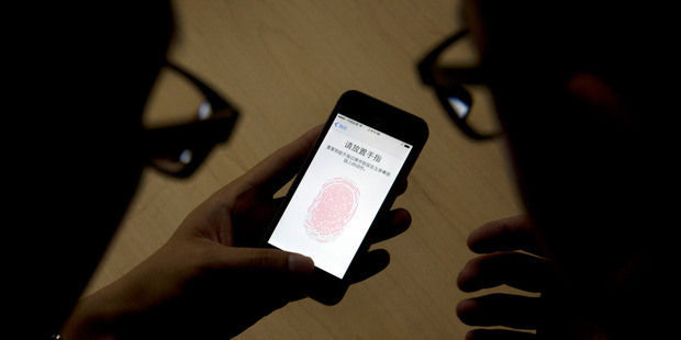 An Apple employee, right, instructs a journalist on the use of the fingerprint scanner technology built into the company's iPhone 5S during a media event held in Beijing, China. Photo / AP