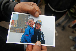 A family member holds a photo showing Josef Hector, right, who was shot dead in the township of Manenberg on the outskirts of Cape Town, South Africa. Photo / AP