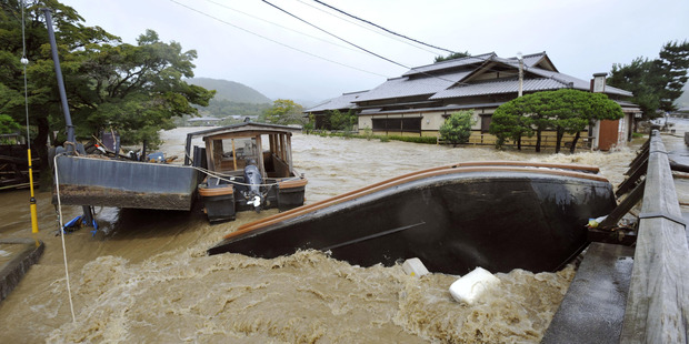 An overturned sightseeing boat is stuck by a bridge after the Katsura River was overflooded by torrential rains in the popular tourist destination of Kyoto. Photo / AP