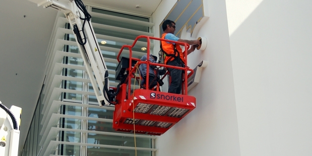Contractors at work yesterday putting the finishing touches to exterior signage and lighting. Photo / Paul Taylor