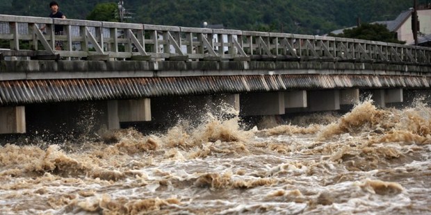 Muddy water of the Katsura river runs under a bridge in Kyoto as torrential rain hit western Japan. Photo / AFP