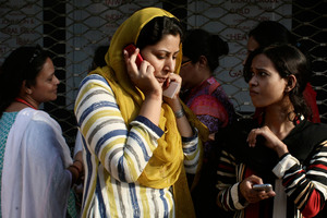 A Pakistani woman speaks on her mobile phone after rushing out of her apartment following a major earthquake that struck Baluchistan province in southwest Pakistan. Photo / AP