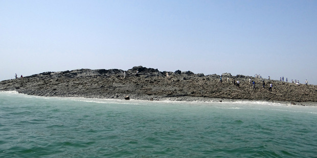 People walk on an island that reportedly emerged off the Gwadar coastline in the Arabian Sea. Photo / AP