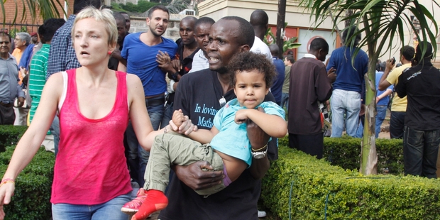 A security guard helps a mother and her child outside the upmarket Westgate Mall in Nairobi after gunmen threw grenades and opened fire. Photo / AP