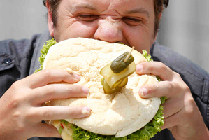 Herald reporter Jamie Morton tackles the challenge of eating the Jumbo Beef Burger from Angelo's Pizza in Waihi. Photo / Christine Cornege