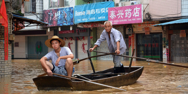 Residents paddle a boat in flood waters triggered torrential rains from typhoon Utor on a street in Fengkai in south China's Guangdong province.Photo / AP