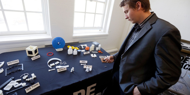 Aaron Kemmer, CEO and co-founder of Made in Space, looks through some items made with the company's 3D printer which will eventually be used in space. Photo / AP