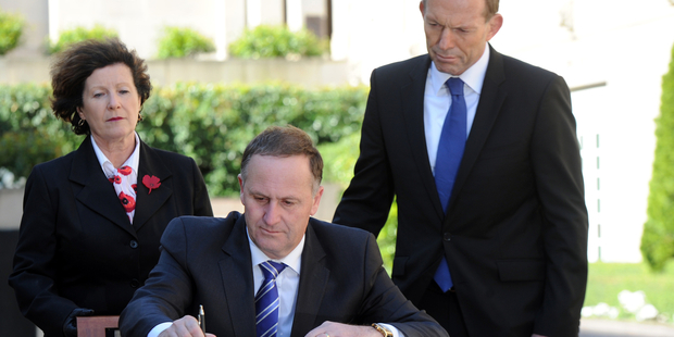 New Zealand Prime Minister John Key signs the visitors book, watched by the Australian Prime Minister Tony Abbott, at the Australian War Memorial in Canberra. Photo / SNPA