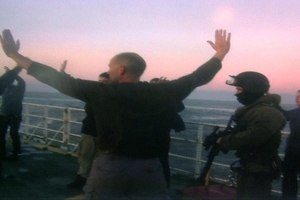 Greenpeace protesters surrender to Russian Coast Guards after their ship was boarded. The image was taken from a computer screen. Photo / AP