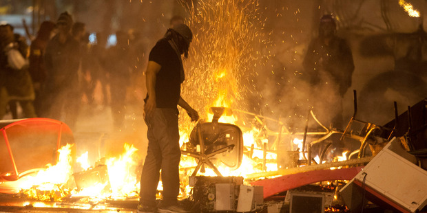 A demonstrator with his face covered stands next a burning barricade near the Cinelandia square after a march in support of teachers on strike in Rio de Janeiro, Brazil. Photo / AP