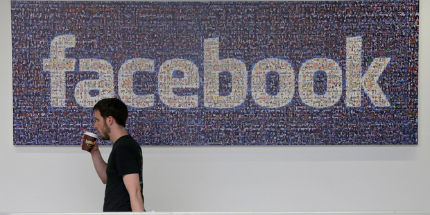 A Facebook employee walks past a sign at Facebook headquarters in Menlo Park, California.