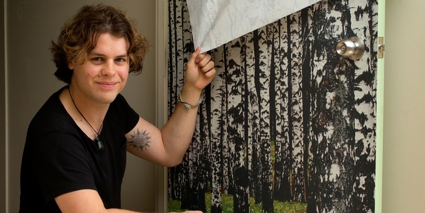 Designer Antony Clark demonstrates the removable, reusable wallpaper. Photo / Brett Phibbs