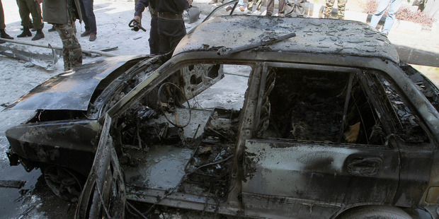 A damaged vehicle smolders after firefighters extinguish a fire on it following two mortar rounds struck the Abu Roumaneh area in Damascus, Syria. Photo / AP