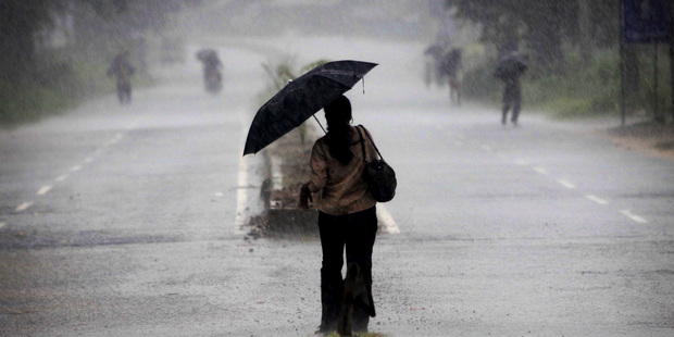 An Indian woman holds an umbrella as she heads towards a cyclone shelter near Chatrapur in Ganjam district. Photo / AP