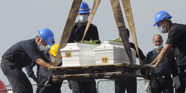 The caskets of two children who died when their boat capsized off in the Canal of Sicily are lifted to be embarked on a Italian Navy ship at the Lampedusa island harbor. Photo / AP