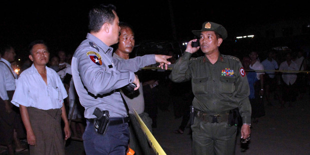 A Myanmar police officer, front left, talks with an army officer as they examine the scene of an explosion. Photo / AP
