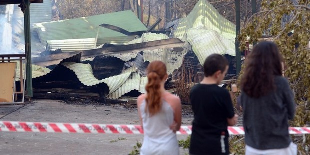 Children look at a house burnt out by bushfires in Winmalee in Sydney's Blue Mountains. Photo / AFP