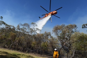A firefighter looks on as air crane Elvis drops water at the Linksview Rd fire near Faulconbridge. Photo / AAP