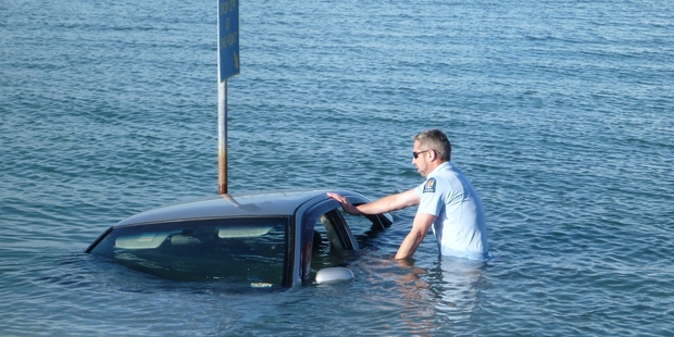 Mel Hunter, police officer, wades out to check the submerged car found in Napier yesterday. Photo / Supplied