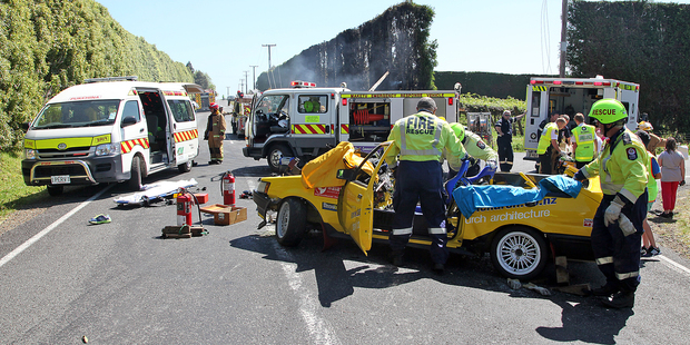 Bystanders race to the aid of Dave West after his Toyota Corolla GT slammed into a concrete power pole causing a fire.