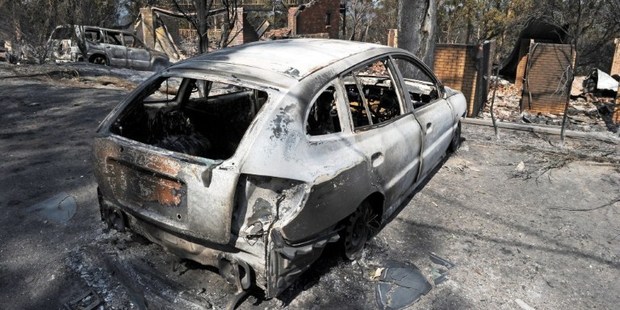 A burnt out car sits in front of a house destroyed by bushfires in Winmalee in Sydney's Blue Mountains. Photo / AFP