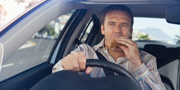 Driving a car and eating can be hazardous. Photo / Getty Images