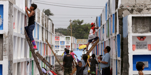 Filipino Catholics spruce up the crypts of their loved ones at a public cemetery at Paranaque city, south of Manila, Philippines. Photo / AP