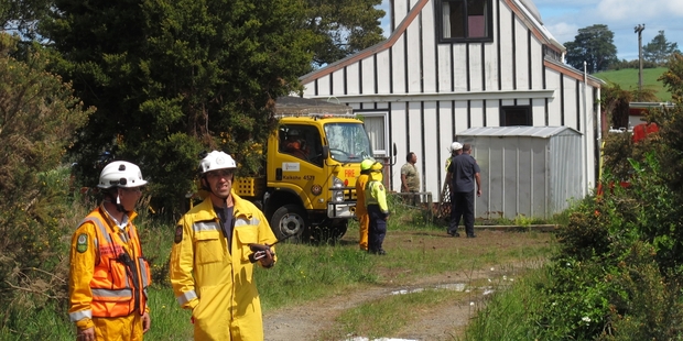 Rural firefighters guard one of two threatened houses on Mangakahia Rd.