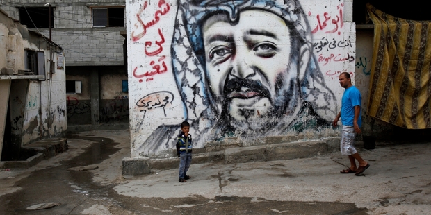 Palestinians walk past a mural depicting Yasser Arafat at Shati Refugee Camp, in Gaza City. Most Palestinians blame Israel for his death.Photo / AP