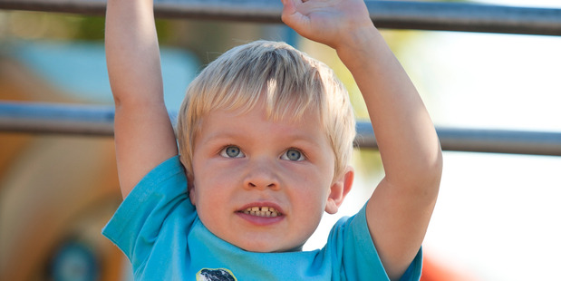 Trying out the monkey bars on the new playground at Omana Regional Park.