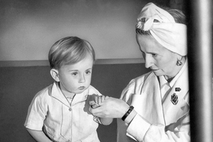 Physical therapist Estrid Dane supports two-year-old Anthony Bull who is suffering from toickets in 1943 .Photo / AP