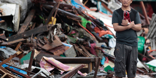A resident looks at houses damaged by typhoon Haiyan, in Tacloban city. Photo / AP