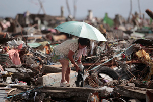 A survivor salvages belongings from her damaged home. Photo / AP