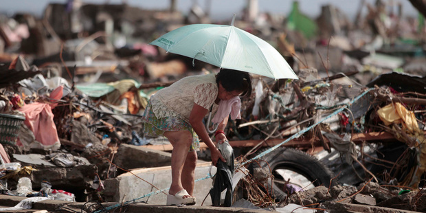A survivor salvages belongings from her damaged home. Photo / AP