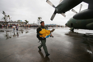 A trooper carries an elderly woman to a military plane. Photo / AP