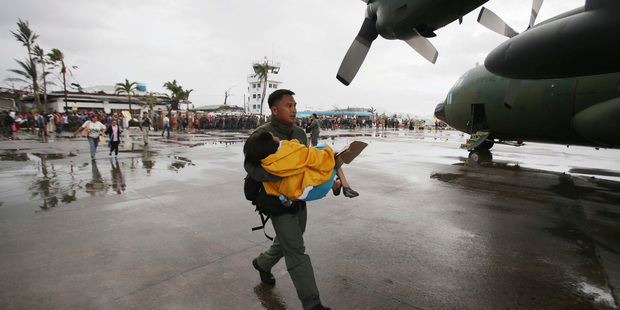 A trooper carries an elderly woman to a military plane. Photo / AP