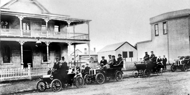 Historic Auckland A convoy of cars ready for an afternoon run, waiting outside the Criterion Hotel, Otahuhu in 1903. The first car, driven by a man in a peaked cap, is steered by a tiller.