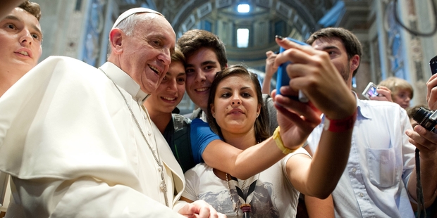Pope Francis embraces the smartphone selfie with young people in Rome.