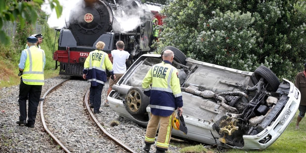 Emergency workers clear the car off the track near Wanganui as the train waits. Photo / APN