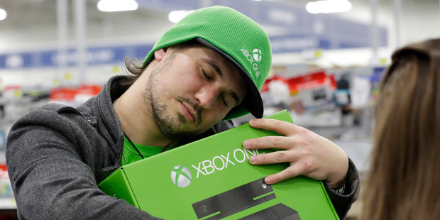 Emanuel Jumatate, from Chicago, hugs his new Xbox One after he purchased it at a Best Buy in Evanston, Ill. Photo / AP