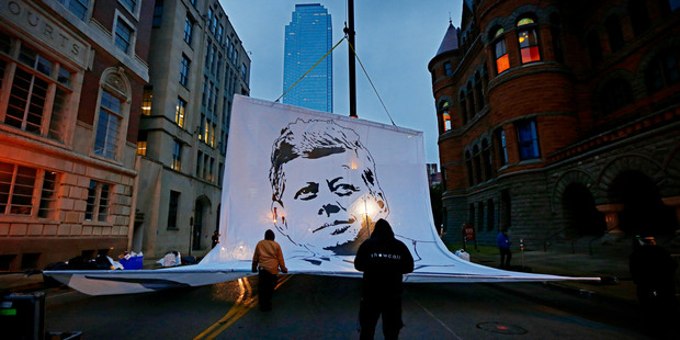 Crews raise a large banner on Main Street before the start of a ceremony to mark the 50th anniversary of the assassination of John F. Kennedy. Photo / AP