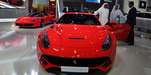 Emirati visitors examine the Ferrari F12 berlinetta at the Dubai International Motor Show in Dubai, United Arab Emirates, Tuesday Nov. 5, 2013. Photo / AP