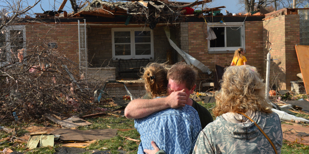 Ray Baughman embraces family shortly after his home was destroyed by a tornado that left a path of devastation through the north end of Pekin, Illinois. Photo / AP