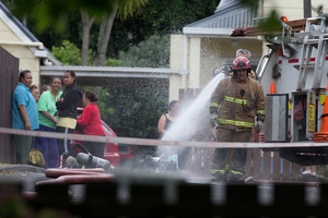 Firefighters douse hot spots at the Onehunga house after yesterday's fatal fire. Photo / Brett Phibbs