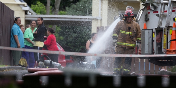 Firefighters douse hot spots at the Onehunga house after yesterday's fatal fire. Photo / Brett Phibbs