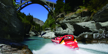A Shotover jet roars up the canyon towards the Edith Cavell Bridge.