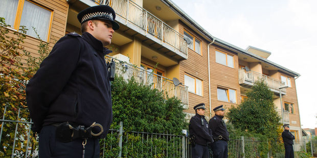 Police officers stand outside flats in the area where three women were rescued in south London. Photo / AP