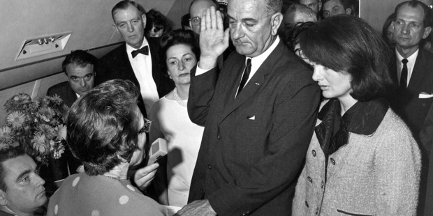 Lyndon B. Johnson is sworn in as president as Jacqueline Kennedy stands at his side, in her famous bloodstained pink suit. Photo / AP Images