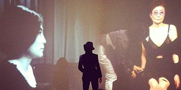 Yoko Ono stands between two screens showing her performing Cut Piece in 1965 and 2003 at the Museum of Contemporary art in Sydney.