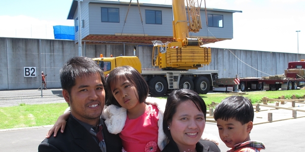 The Constantino family of Dargaville outside Ngawha prison yesterday as their new house built by prisoners was lifted over the wire. Photo/Peter de Graaf.